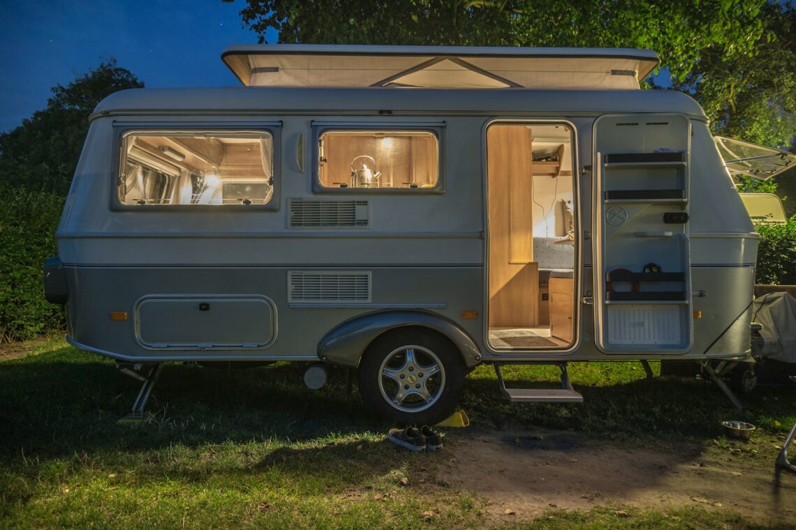 caravane blanche et marron à côté d'un arbre