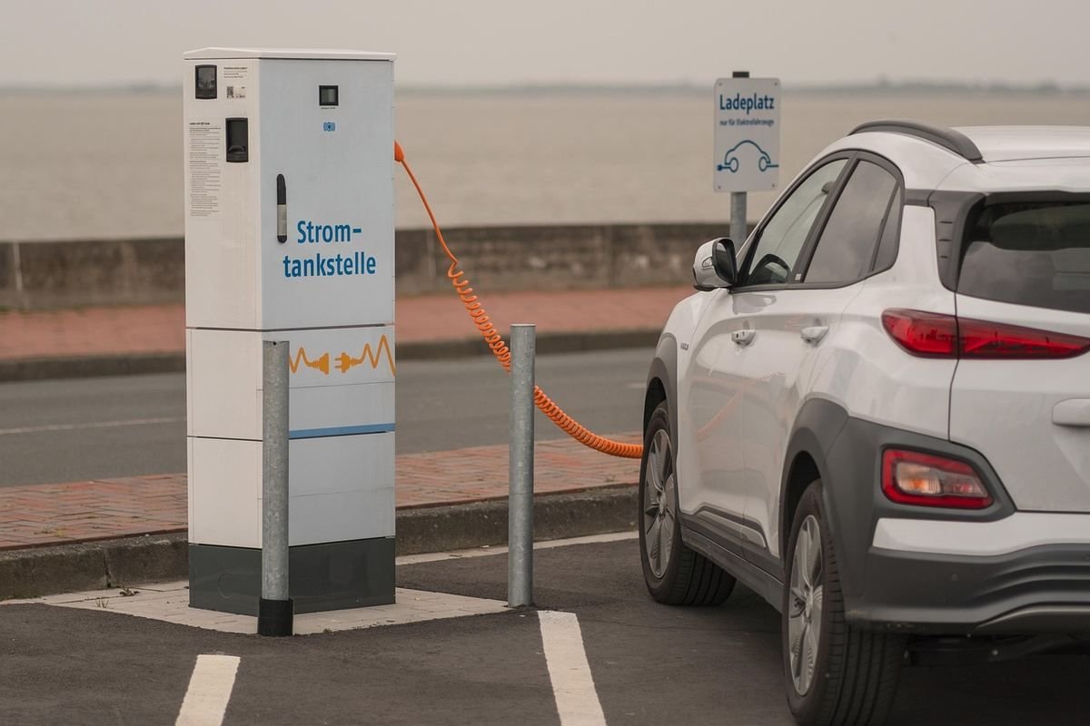 Voiture électrique blanche connectée à une borne de recharge publique en parking