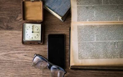 livre ouvert, montre, smartphone, lunettes et boîte sur table en bois