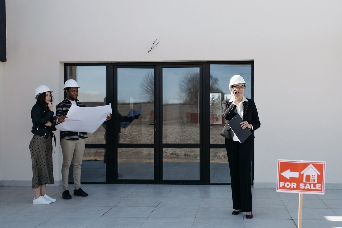 Professionnels en casques d'architecte devant un bâtiment avec panneau Professionnels en casques d'architecte devant un bâtiment avec panneau