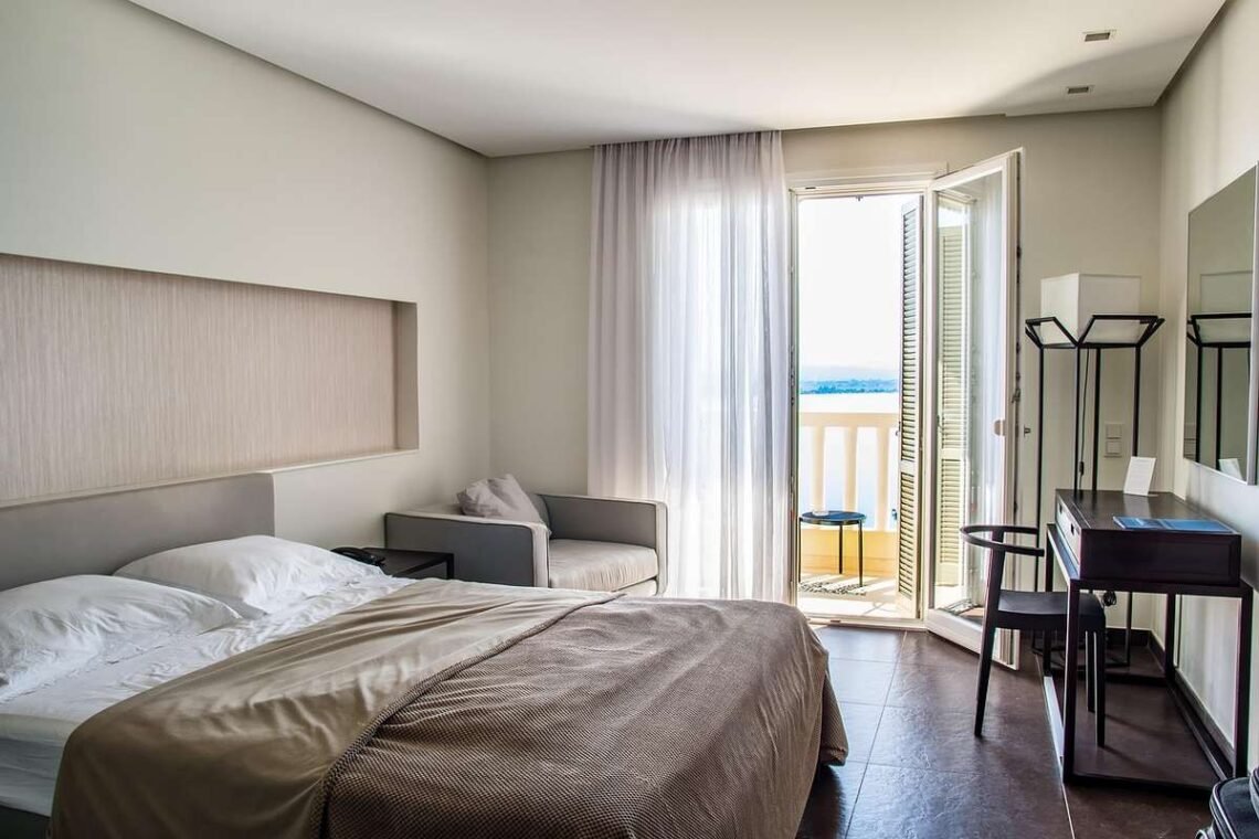 Une chambre moderne avec lit chaise table et porte-balcon ouvrant sur la mer