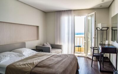 Une chambre moderne avec lit chaise table et porte-balcon ouvrant sur la mer