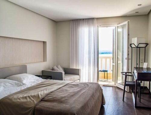 Une chambre moderne avec lit chaise table et porte-balcon ouvrant sur la mer