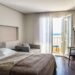 Une chambre moderne avec lit chaise table et porte-balcon ouvrant sur la mer