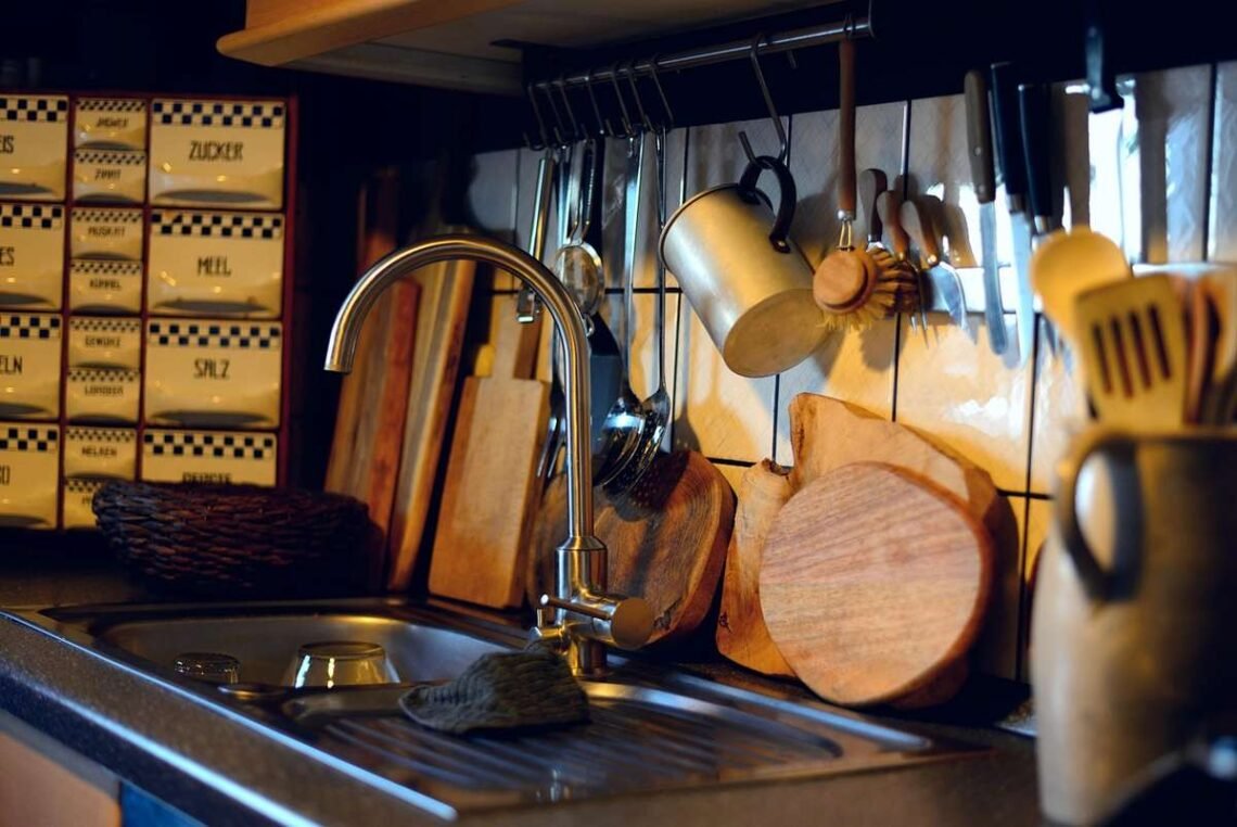 Vue d'une cuisine avec évier, robinet, plan de travail et ustensiles accrochés