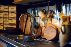 Vue d'une cuisine avec évier, robinet, plan de travail et ustensiles accrochés