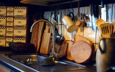 Vue d'une cuisine avec évier, robinet, plan de travail et ustensiles accrochés
