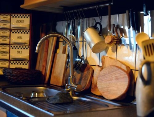 Vue d'une cuisine avec évier, robinet, plan de travail et ustensiles accrochés