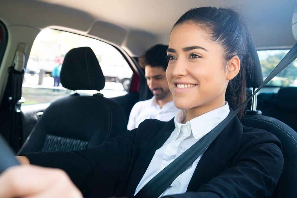 Une femme souriante conduit, passager assis, ceintures, intérieur automobile