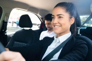 Une femme souriante conduit, passager assis, ceintures, intérieur automobile