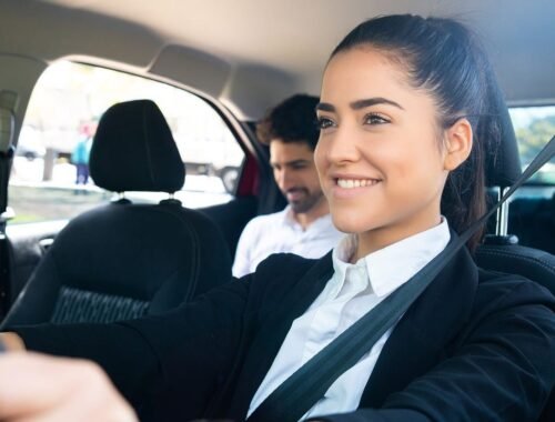 Une femme souriante conduit, passager assis, ceintures, intérieur automobile