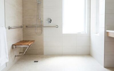 Salle de bain accessible senior, douche de plain-pied avec barre d'appui et siège, carrelage clair, lumineuse
