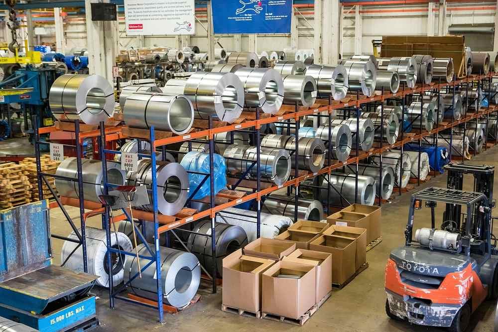 Rouleaux d'acier empilés sur des étagères dans un entrepôt industriel