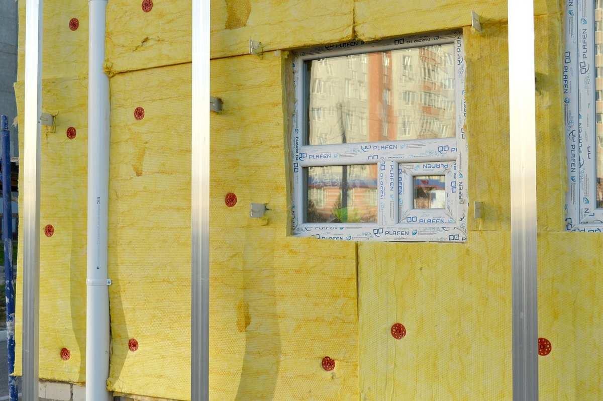 Vue d'une façade en construction avec isolation jaune et fenêtre Vue d'une façade en construction avec isolation jaune et fenêtre