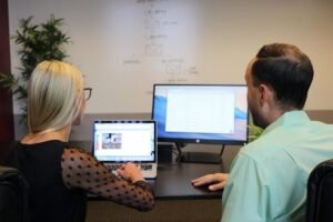 Deux personnes travaillent ensemble sur ordinateur portable et écran