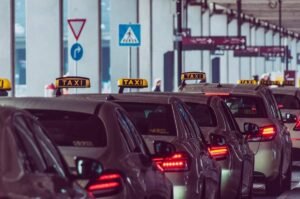 File de taxis devant un édifice, feux arrière allumés, panneaux de signalisation visibles