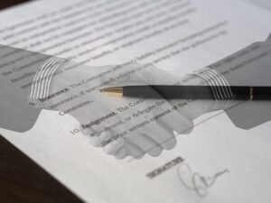 Mains serrées sur un papier avec une plume posée dessus, signature en bas