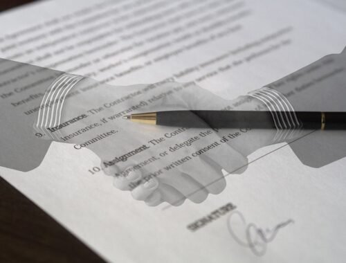 Mains serrées sur un papier avec une plume posée dessus, signature en bas