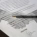Mains serrées sur un papier avec une plume posée dessus, signature en bas