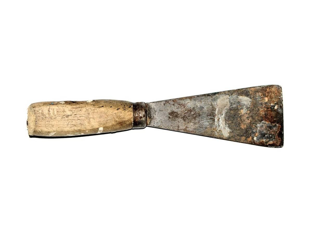 Un couteau à enduire usé avec manche en bois, métallique, posé horizontalement